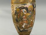 a gold vase with a painting on it sitting on a table