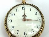 a close up of a pocket watch on a white surface