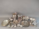 a pile of silver dishes and silverware on a table