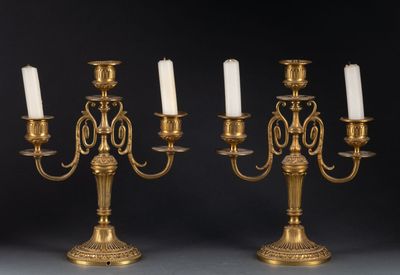 une paire de chandeliers anciens en laiton avec des bougies blanches
