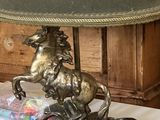 une lampe sur laquelle est représenté un cheval, posée sur une table