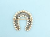 an image of a brooch with pearls and diamonds on a blue background