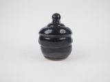small black ceramic jar with lid on white background