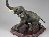 statue of an elephant with tusks standing on a rock