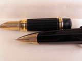 pair of black and gold fountain pens sitting on top of a white cloth