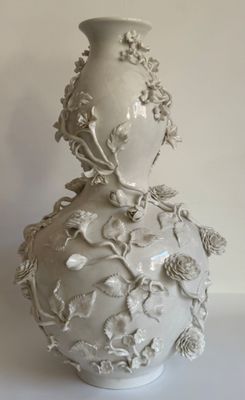 un vase blanc avec des fleurs posé sur une table