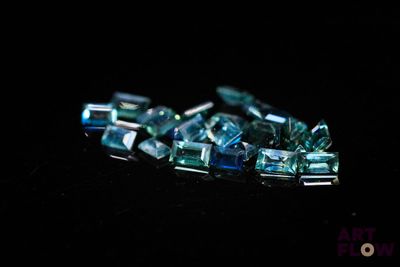 plusieurs morceaux de verre bleu et vert posés sur une surface noire