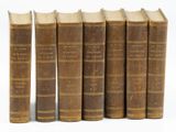 six vieux livres alignés sur une surface blanche