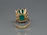 a close up of a gold ring with a green stone in it