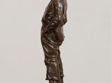 bronze statue of a boy standing on a base with his hands in his pockets