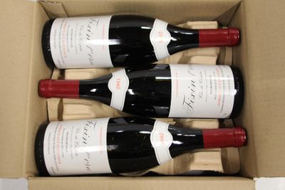 four bottles of wine in a cardboard box on a table