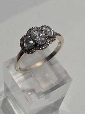 une photo d'une bague en diamant à trois pierres présentée sur un présentoir transparent