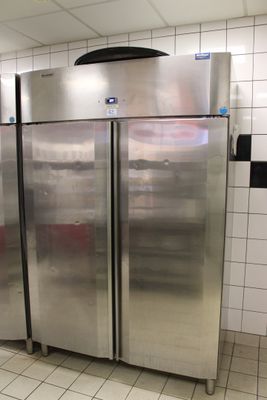 des réfrigérateurs en acier inoxydable dans une cuisine professionnelle aux murs carrelés