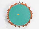 a green circular object hanging on a white wall
