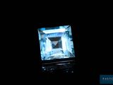 Une pierre de topaze bleu aqua est mise en valeur dans l'obscurité