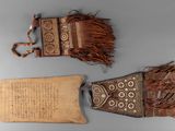 two pieces of leather with fringes and a piece of paper on a table