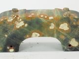 une sculpture représentant un ours, de couleur verte et jaune, posée sur une surface blanche