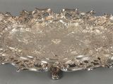 une assiette en argent ornée d'un motif décoratif sur un fond gris