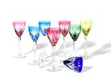 Des verres à vin aux couleurs vives sont alignés en rangée sur une surface blanche