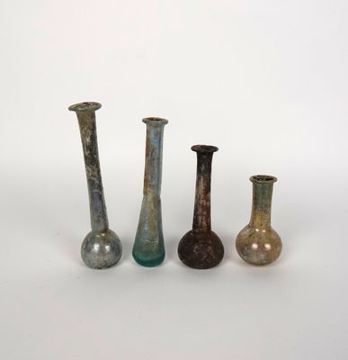 quatre vases en verre de couleurs différentes posés les uns à côté des autres sur une surface blanche