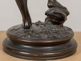 a bronze statue of a woman bending over on a table