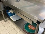 une table en acier inoxydable dans une cuisine, sur laquelle sont posées des casseroles et des poêles