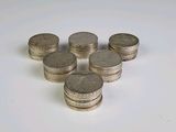 several stacks of silver coins sitting on top of a white surface