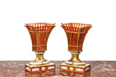 deux vases dorés posés sur une table, sur fond blanc