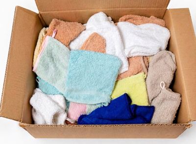 une boîte en carton remplie de serviettes de toutes sortes posée sur une surface blanche