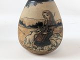 un petit vase avec une peinture sur une surface blanche