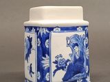 a blue and white vase with a woman holding a flower