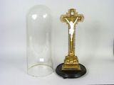 a gold cross on a pedestal next to a glass bell jar