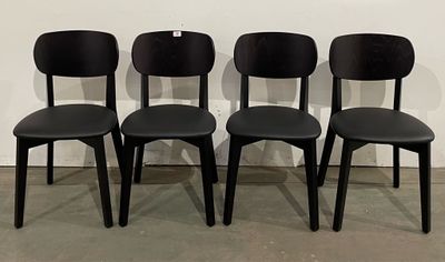 quatre chaises noires sont alignées contre un mur blanc