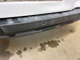 the front bumper of a white car with dirty paint on it