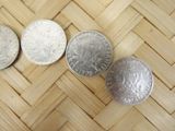 three different types of silver coins on a woven surface