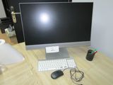 un écran d'ordinateur et un clavier posés sur un bureau, avec une lampe