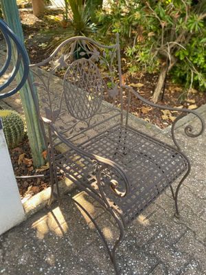 a metal bench sitting on the sidewalk next to a cactus plant