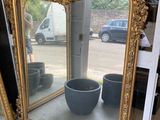 un grand miroir posé par terre à côté d'une plante en pot