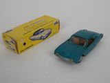 une petite voiture bleue et une boîte jaune posées sur une surface blanche