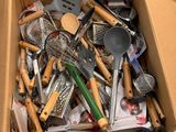une boîte remplie d'ustensiles de cuisine posée par terre