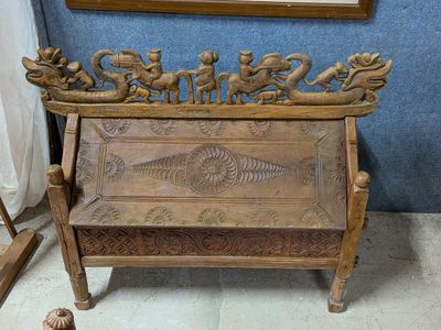 un banc en bois orné de sculptures, placé devant un miroir