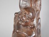 a wooden statue of a child with a clock in the background