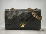 un sac Chanel noir avec des finitions dorées et une chaîne