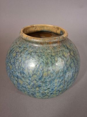 un vase bleu et vert posé sur une surface blanche