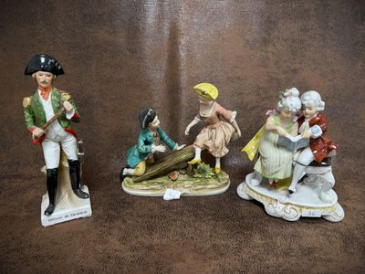three figurines of people sitting on top of a brown surface