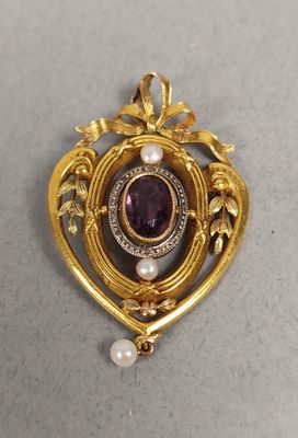 un gros plan d'une broche en or ornée d'une pierre violette entourée de perles