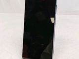 a black cell phone sitting on a stand on a white surface