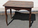 a small wooden table with a wooden top on the pavement