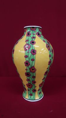 un vase jaune orné de fleurs rouges sur fond rouge