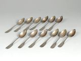 six cuillères en argent sont disposées en ligne sur une surface blanche